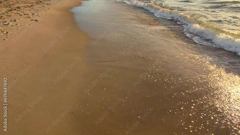 Sea waves rolling onto the sandy beach of the seashore on a sunny morning at dawn. Sea waves with foam and splashes on sand of the shore. Coast Seaside Seashore. Natural background. Nature backdrop. Sea waves rolling onto the sandy beach of the seashore on a sunny morning at dawn. Sea waves with foam and splashes on sand of the shore. Coast Seaside Seashore. Natural background. Nature backdrop.