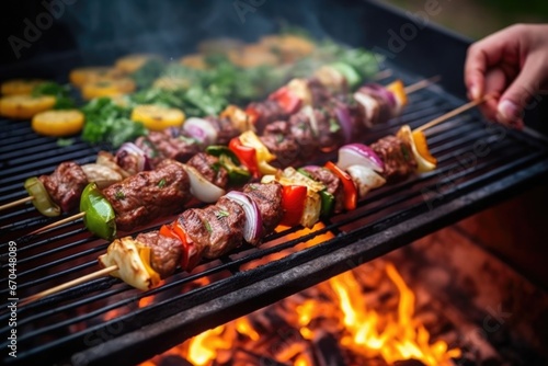human hand grilling a bunch of mediterranean kebabs