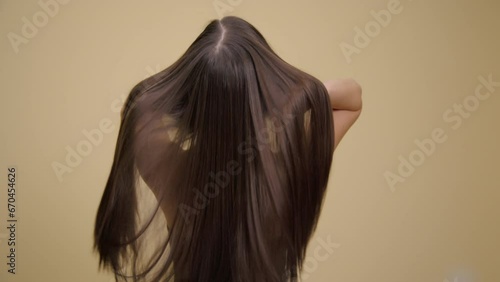 Luxurious long brunette hair. Back view. Yellow background.