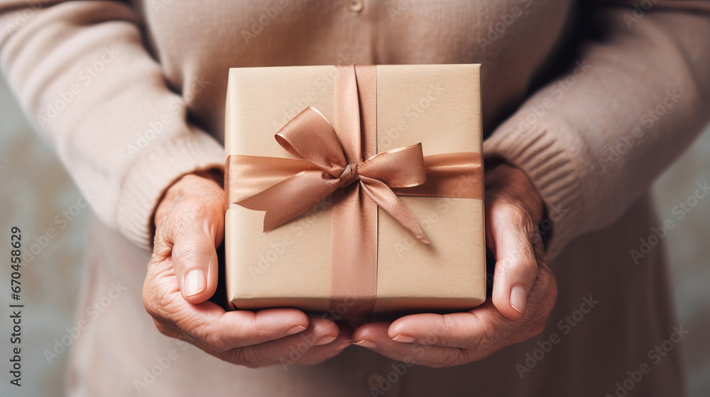 Close-up present box in mature female hands. Celebrating Mother's Day, Christmas. Gifts for parents background Close-up present box in mature female hands. Celebrating Mother's Day, Christmas. Gifts for parents background
