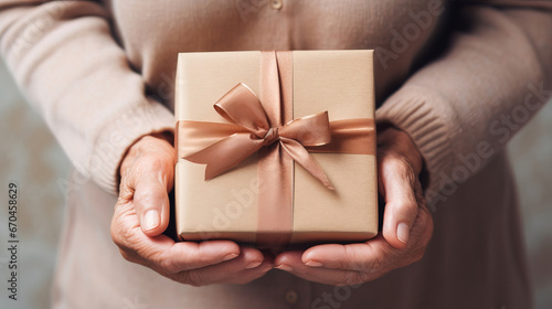 Close-up present box in mature female hands. Celebrating Mother's Day, Christmas. Gifts for parents background