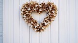 A heart-shaped wreath made of dried leaves hanging on a white door, a symbol of nature's embrace.
