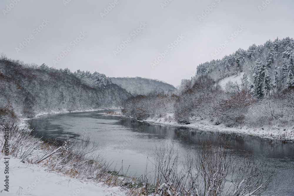 Winter river in snow landscape. Wonderful winter scene. Frosty, misty morning on big river. Europe. Ukraine. Spruce, tree forest covered fresh snow and frost during Christmas time. Nature background.