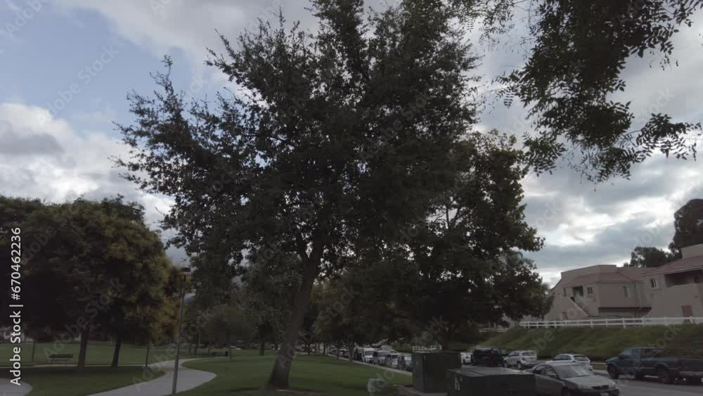 Light wind moving tree branches and clouds moving over the cars driving in a neighborhood. Timelapse Light wind moving tree branches and clouds moving over the cars driving in a neighborhood. Timelapse