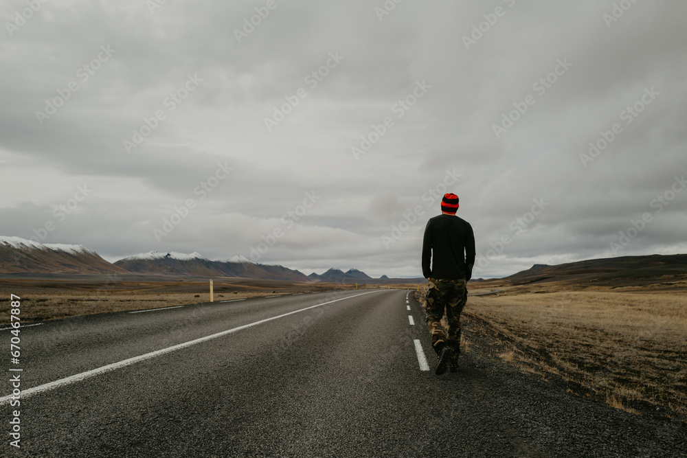 View from behind man walking on the road in Iceland View from behind man walking on the road in Iceland