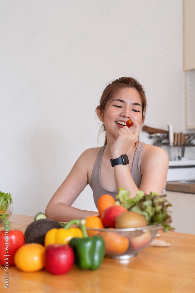 Young Asian healthy beautiful woman with casual clothes is smile and slicing cut tomatoes to eat fruit to diet at home in kitchen in holiday Young Asian healthy beautiful woman with casual clothes is smile and slicing cut tomatoes to eat fruit to diet at home in kitchen in holiday