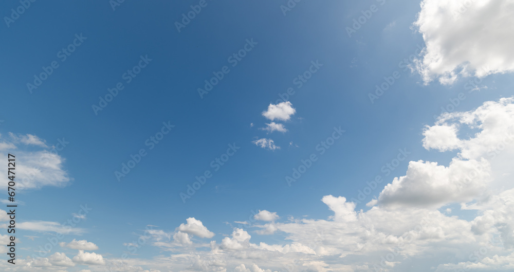 Obraz premium Panoramic view of clear blue sky and clouds, Blue sky background with tiny clouds. White fluffy clouds in the blue sky. Captivating stock photo featuring the mesmerizing beauty of the sky and clouds.