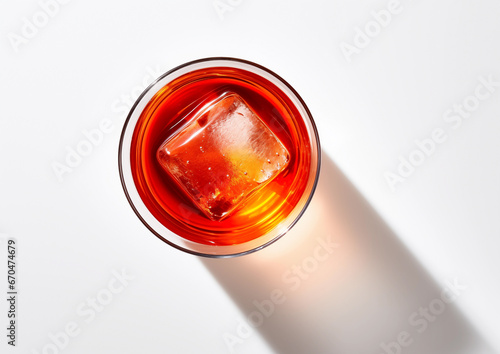Red negroni cocktail with gin and bitters served in glass with ice cube, close up macro overhead with shadow on white background photo