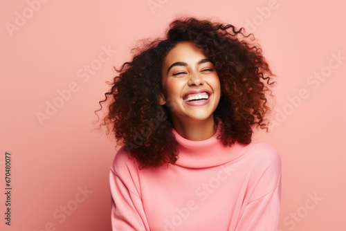 Beautiful young smiling woman in a pink sweater on a pink background