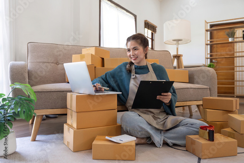 Young woman working online ecommerce shopping at her shop. Young woman seller prepare parcel box of product for deliver to customer. Online selling, ecommerce. Selling products online