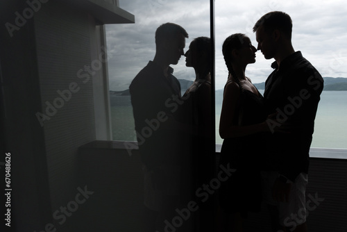 Outline of a couple of lovers posing in a room against the background of a window