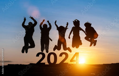 Happy group of people celebrate jump for new year 2024. concept for win victory. silhouette of friends jumps at sunset time on mountains. photo