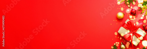 Christmas Present and holiday decorations at red background. Long banner format.