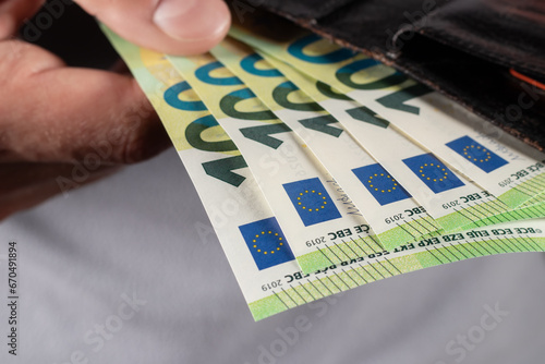 hand pulling 100 Euro banknote from wallet photo