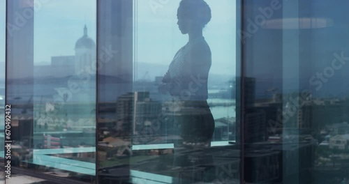Business, woman and window with arms crossed, thinking and ideas in corporate office for review or meeting. Professional, employee and shadow or reflection with leadership, thoughtful and daydreaming photo