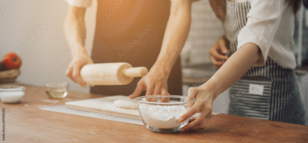 man in apron rolling out dough for homemade pastry, enjoying preparing biscuit cookies in modern light kitchen. man in apron rolling out dough for homemade pastry, enjoying preparing biscuit cookies in modern light kitchen.