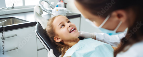 Little cute girl sitting in dental chair while doctor fixing her teeth. Dental care concept. photo
