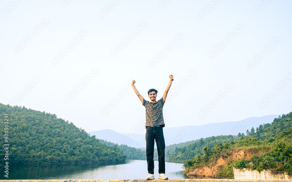 Young asian Indian man with arms raised enjoying the scenic view of the mountains in Jharkhand. Young asian Indian man with arms raised enjoying the scenic view of the mountains in Jharkhand.