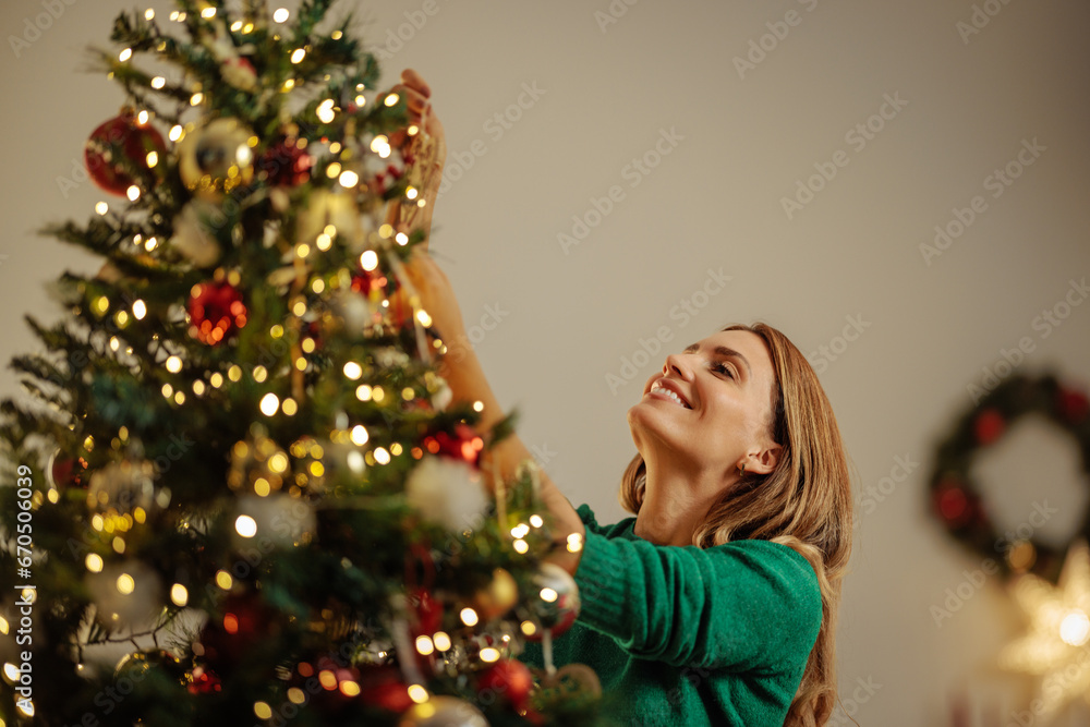 Woman decorating Christmas tree for holidays Woman decorating Christmas tree for holidays