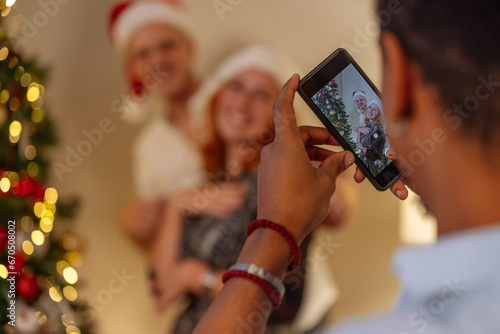A shot of a guy taking a photo of his two friends by a Christmas tree