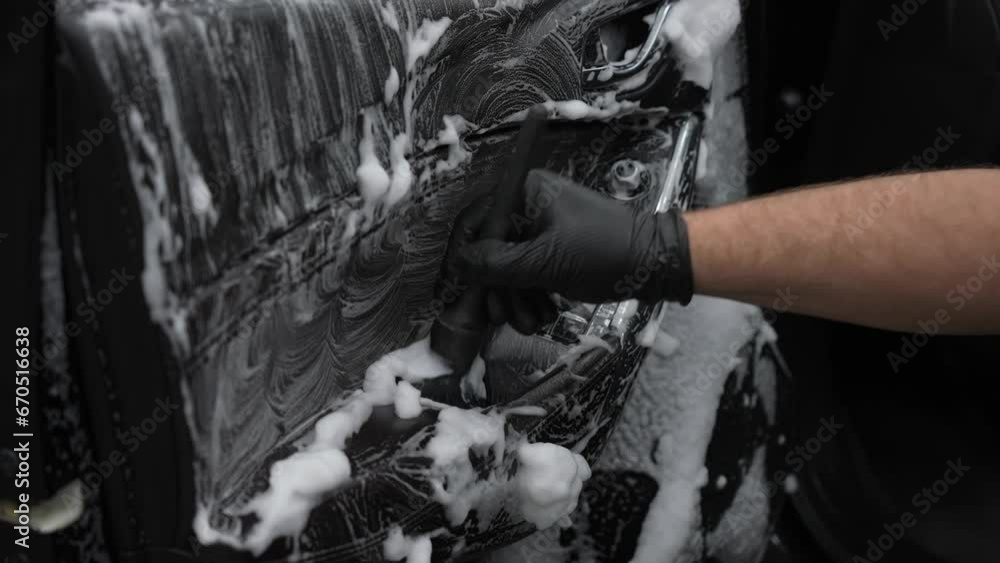 A man cleans the interior of a car with foam and a brush. Clean the door trim. A man cleans the interior of a car with foam and a brush. Clean the door trim.