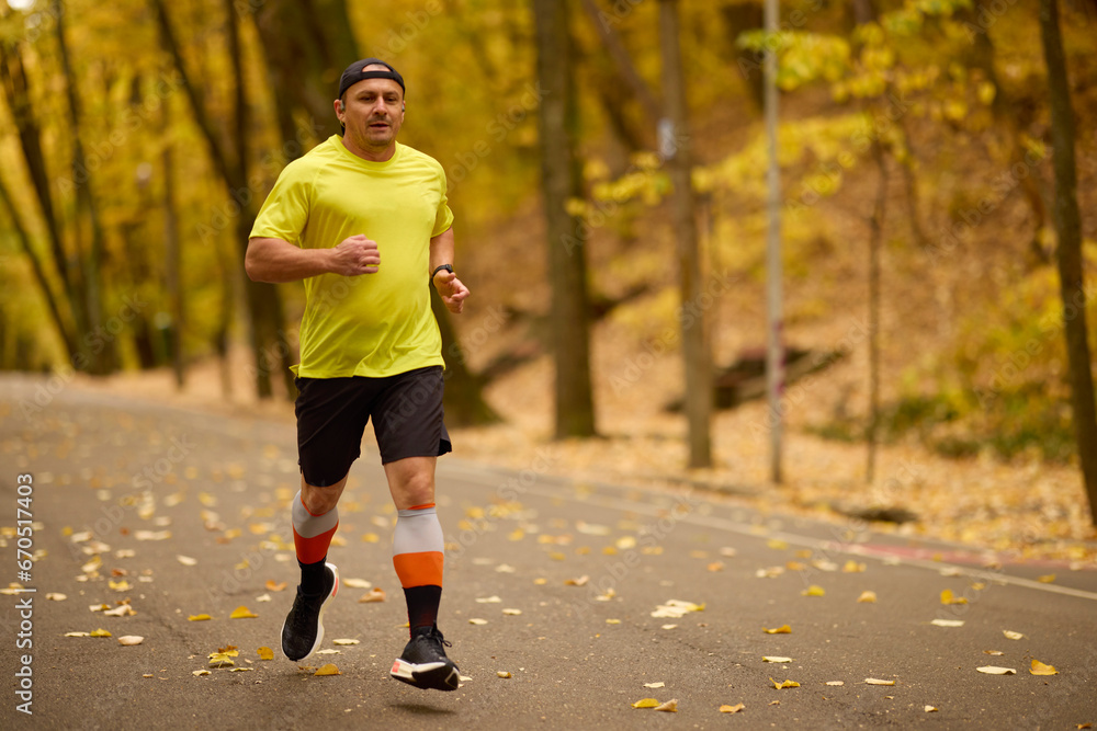 Obraz premium Portrait of a middle-aged man running in the park on an autumn day.