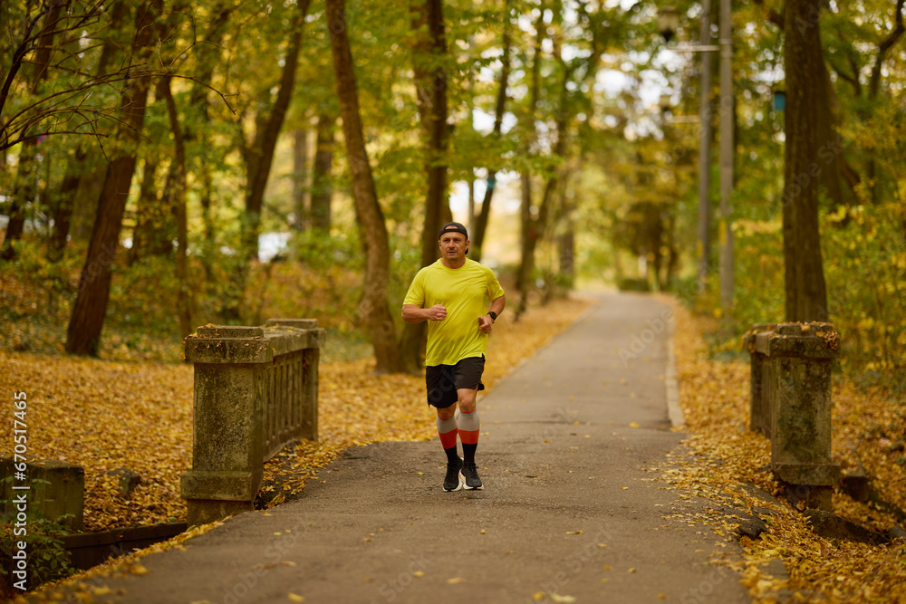 Obraz premium Portrait of a middle-aged man running in the park on an autumn day.