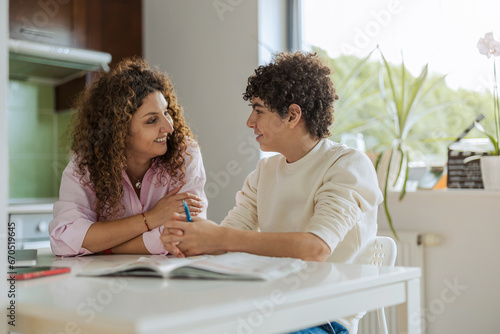 Mother helping her son with homework in kitchen at home
 photo