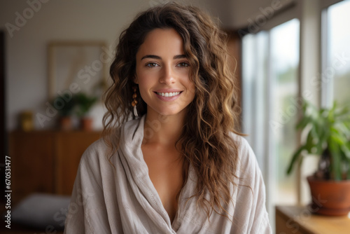 Beautiful young woman in a cotton robe smiling while standing in the living room.