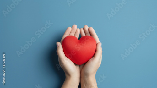 Hands holding a red heart on a blue background.