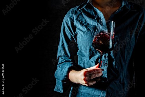 woman hands hold glass red wine on black background