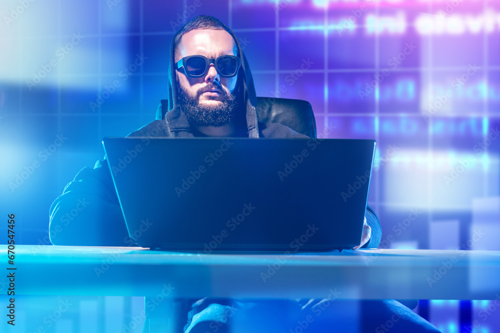 Man is programmer. Computer scientist sits at table with laptop. Hacker in sunglasses. Gamer with computer. Programmer on neon background. Man hacker at work. Cyber security specialist Man is programmer. Computer scientist sits at table with laptop. Hacker in sunglasses. Gamer with computer. Programmer on neon background. Man hacker at work. Cyber security specialist