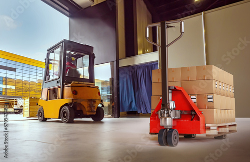 Modern warehouse. Pallet jack with boxes. Forklift for transporting goods. Storage equipment. Industrial hangar with trolleys. Equipment for cargo transportation. Warehouse inside with open gate