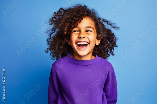 Portrait d'un enfant afro américain portant un pull violet sur fond bleu photo