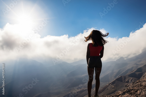 a young girl in a T-shirt and shorts with short hair stands on a high mountain, a girl walks on the top of the mountain photo