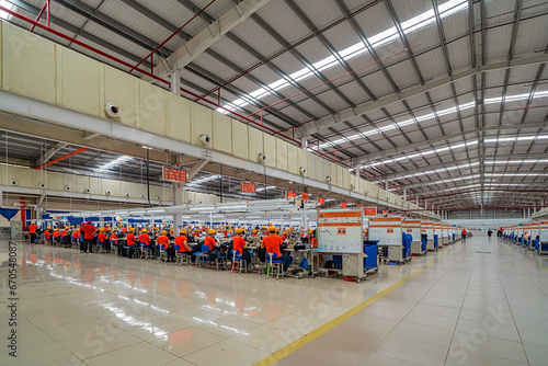 Female worker working in a garment factory in an industrial park in Ho Chi Minh City, Vietnam, with modern machinery and technology systems.