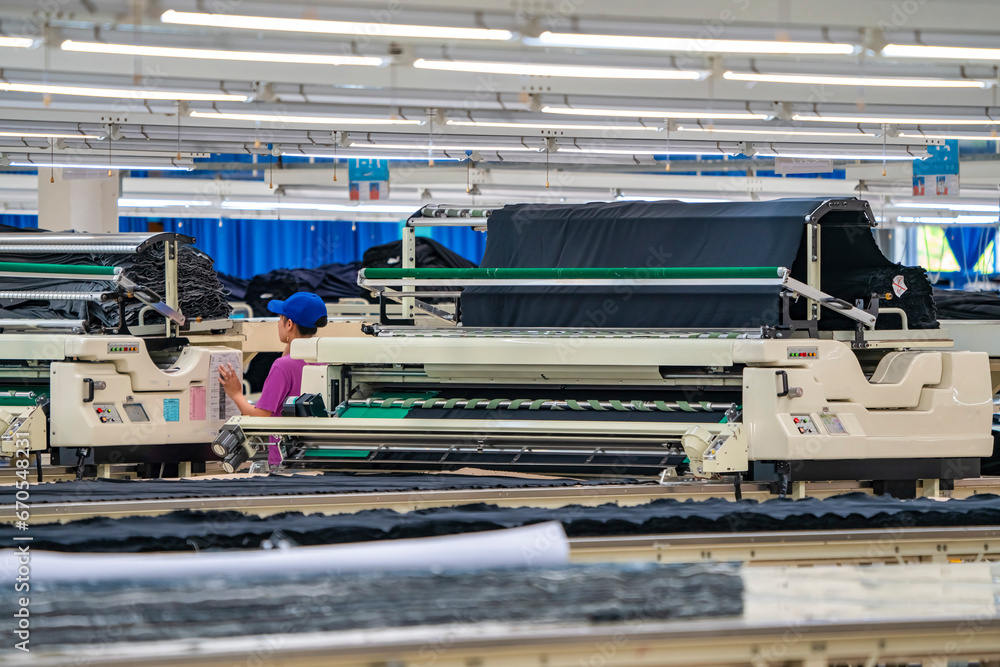 Naklejka premium Industrial cloth cutting machine and fabric cutting area in garment factory in industrial zone in Ho Chi Minh City, Vietnam, with modern machinery and technology systems.