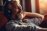 Man listening to music using headphones. is relaxing on the sofa at home.