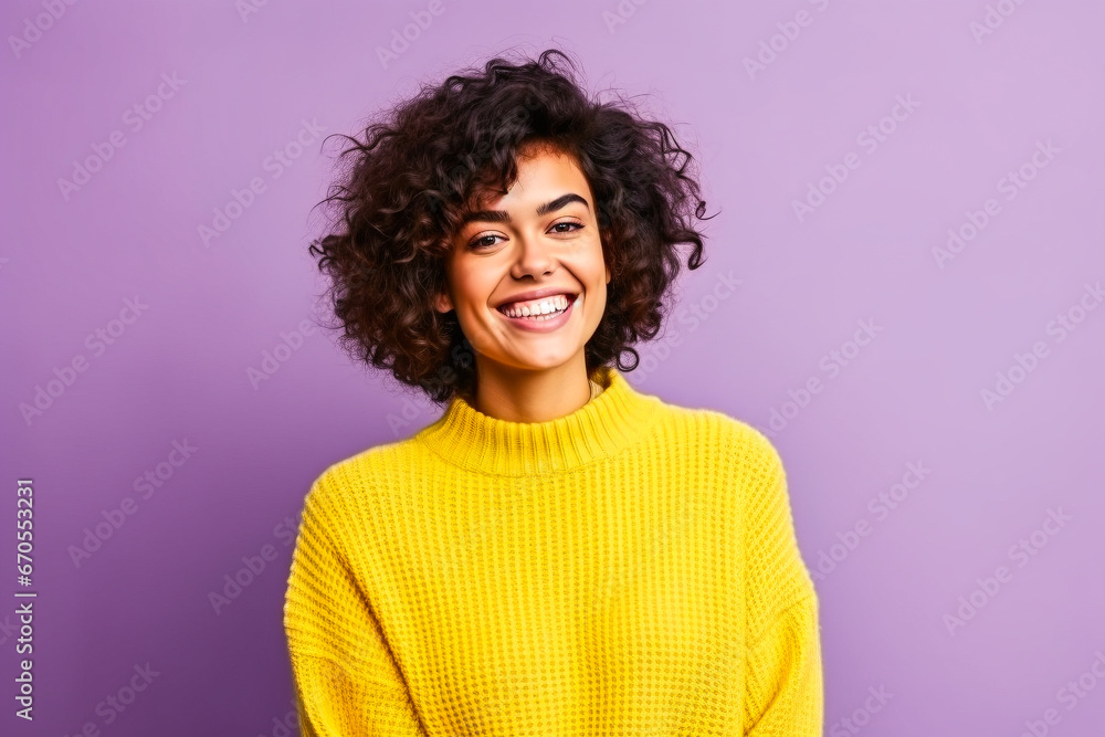Jeune femme souriante portant un pull jaune devant un fond violet Jeune femme souriante portant un pull jaune devant un fond violet