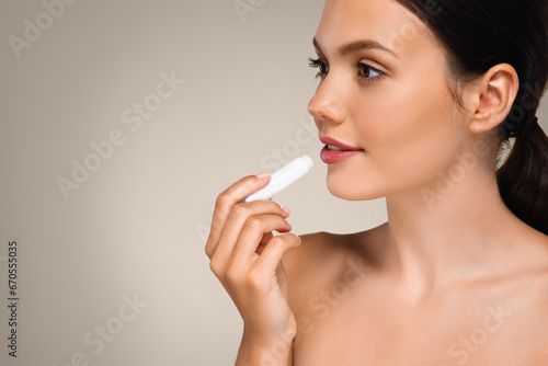 Calm millennial european lady with perfect skin apply lip balm, enjoy routine procedures