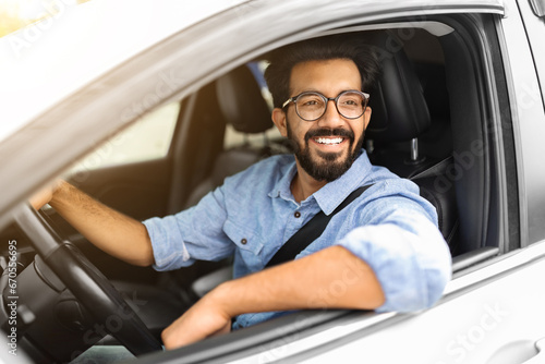 Photo of wealthy eastern businessman in casual driving nice car, © Prostock-studio