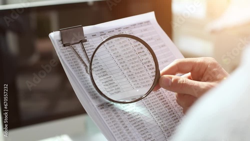 Businessman looking through a magnifying glass to documents