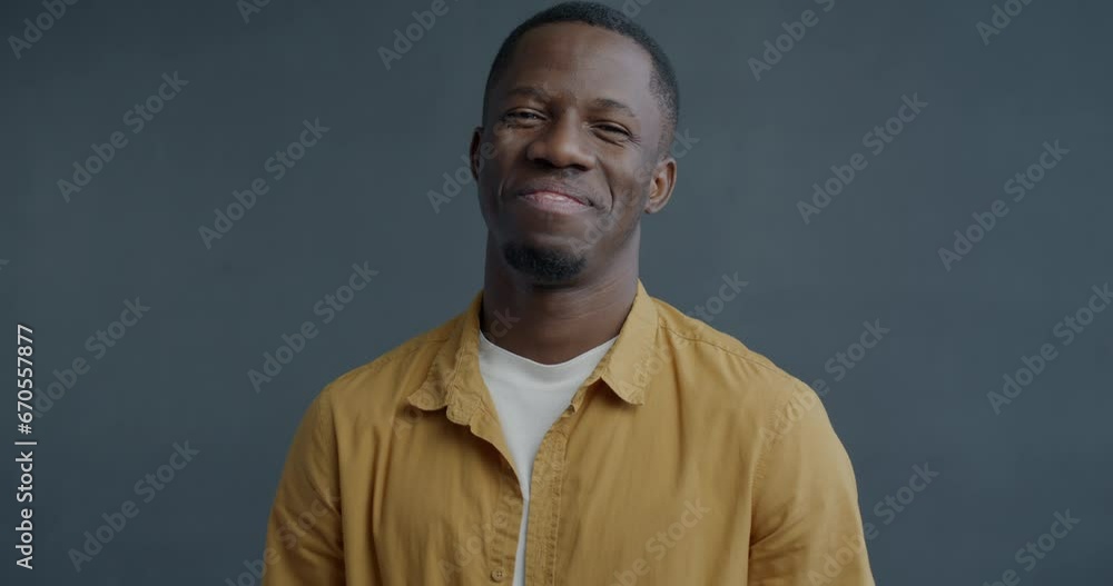 Slow motion portrait of affectionate African American man making beating heart hand gesture and smiling on grey color background. Romantic relationship and love concept. Slow motion portrait of affectionate African American man making beating heart hand gesture and smiling on grey color background. Romantic relationship and love concept.