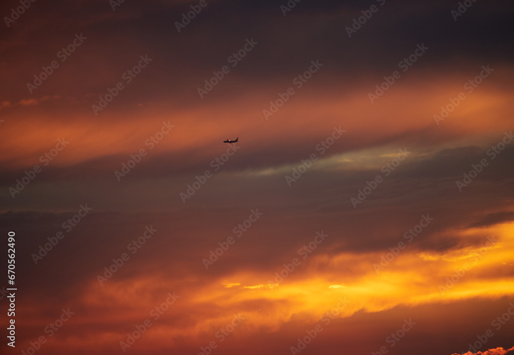 鮮やかな夕焼けの空と飛行中の旅客機の風景