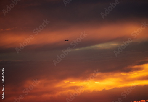 鮮やかな夕焼けの空と飛行中の旅客機の風景