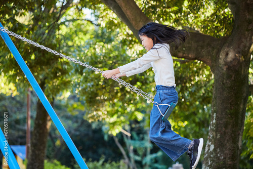 秋の公園でブランコを遊んでいる小学生の女の子の様子