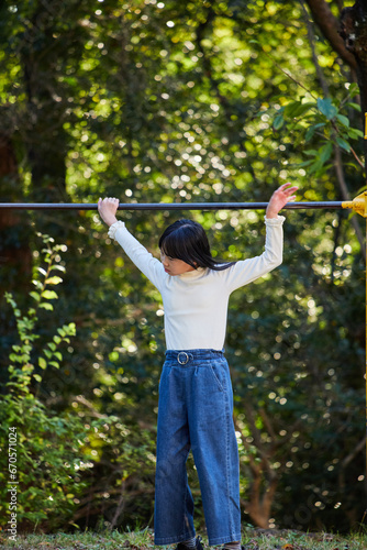 秋の公園で鉄棒を遊んでいる小学生の女の子の様子