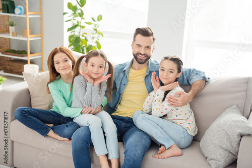 Portrait of four people cheerful guy hugging little girls look camera have good mood weekend home indoors