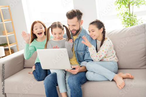 Portrait of four persons sitting on sofa excited arm palm wave look laptop video call have good mood indoors