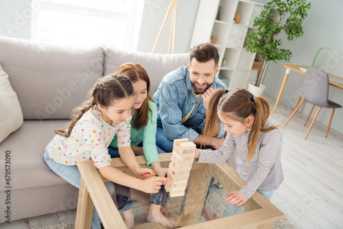 Portrait of attractive cheerful funny family playing building pile stack pyramid free time at home house living-room indoors photo